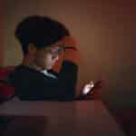 young teen boy looking at his phone while struggling with teen mental health issues