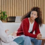 teenage girl and mom are sitting on a couch talking about mental health issues