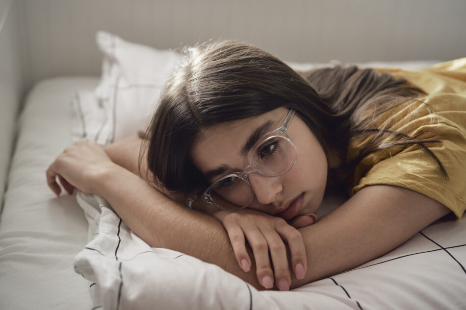 Sad teenage girl lying on bed and looking away with anxiety, demonstrating gad in teens