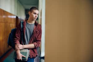 sad teenager standing alone in a school hallway