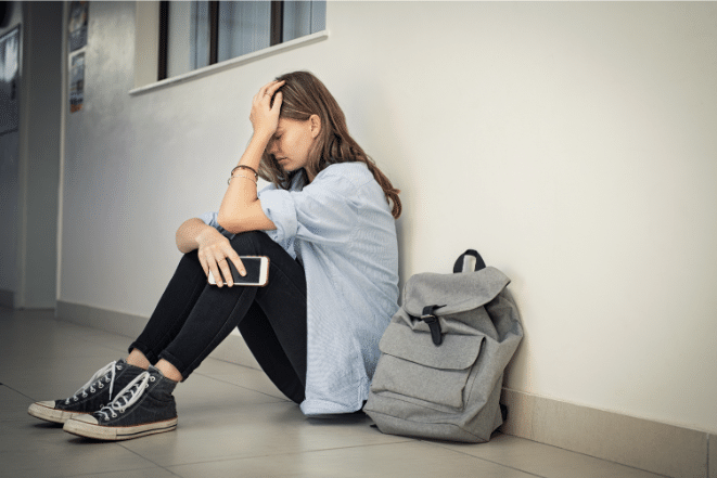 Teen girl sitting on floor with head in hands