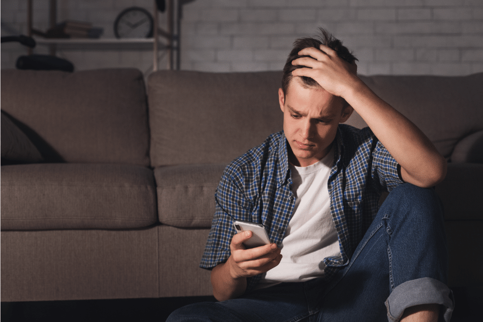 Teen boy leaning on the couch looking at his phone