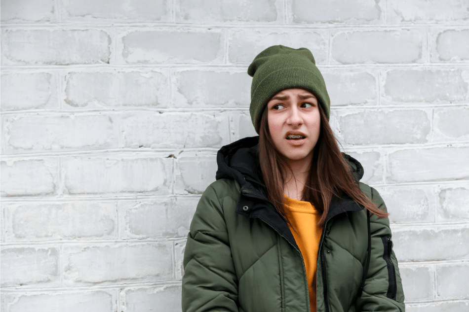 Teenage girl leaning against wall looking annoyed