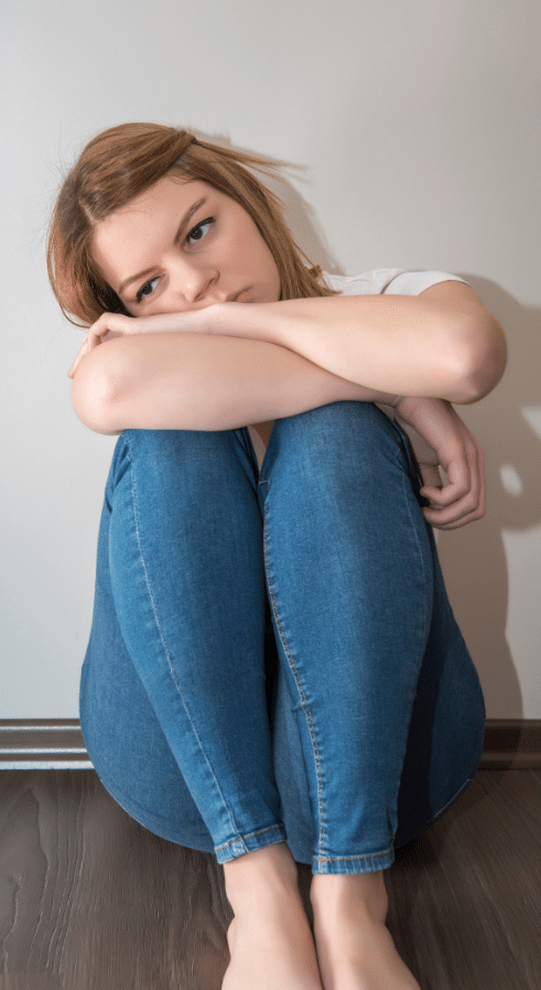 adolescent girl sitting on the floor while struggling with teen mental health