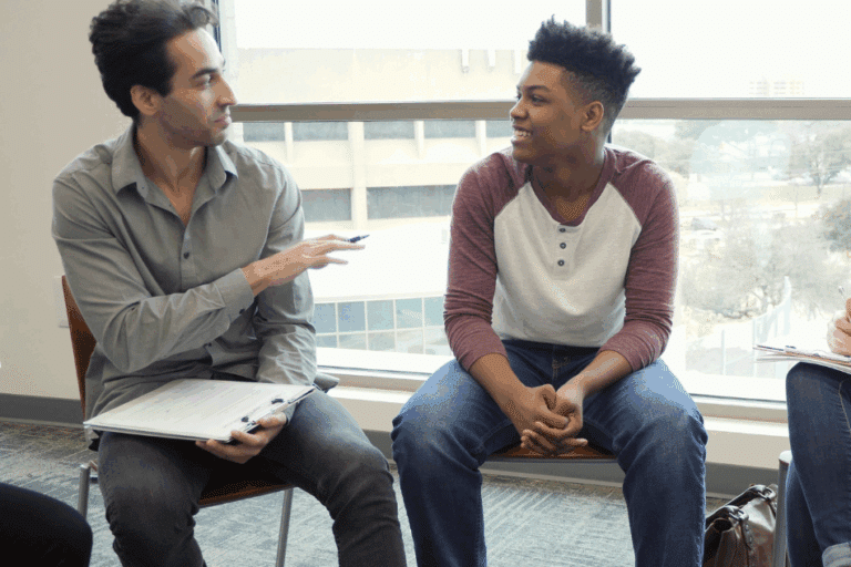 Teen boy sitting in chair next to therapist during therapy session