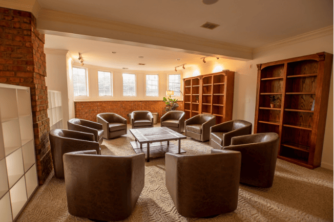 Modern therapy room with circular arrangement of brown leather chairs.