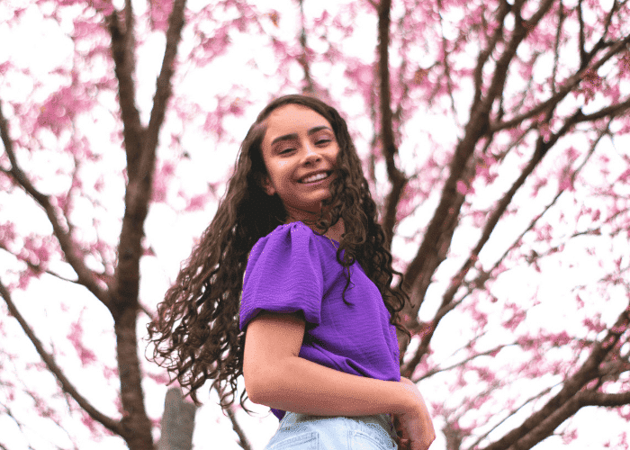 teenage girl smiling in front of blossom tree after effective psychodynamic therapy for teens