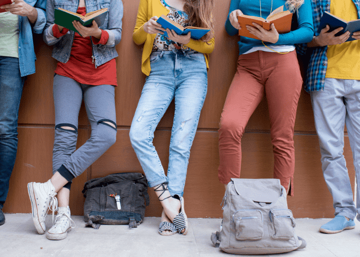 friends leaning against a wall with school books learning the teenage adjustment disorder types