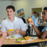 Three teen boys sitting at lunch table eating lunch together
