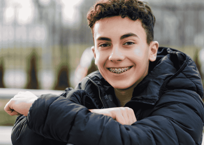 teenage boy with braces smiling at the camera after getting treatment for adjustment disorders in teenagers