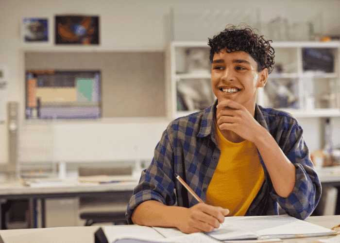 teenage boy holding a pencil and looking happy due to art therapy for emotional expression