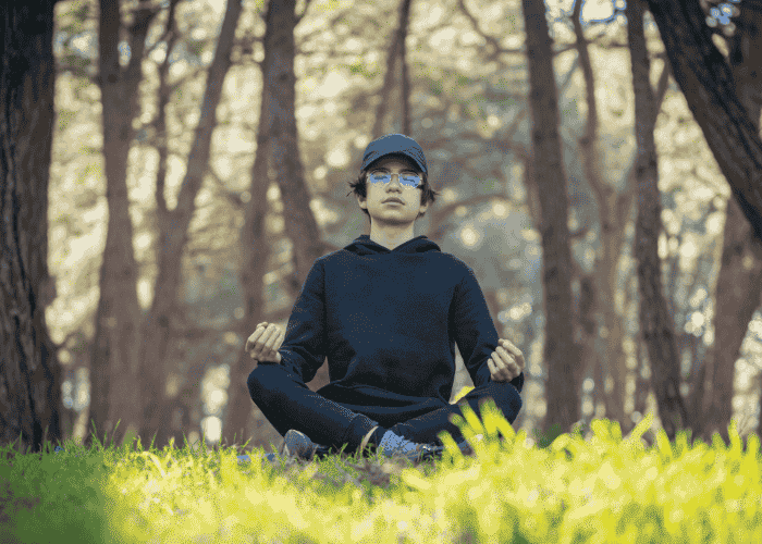 teen boy meditating in woodland as treatment for psychosomatic symptoms