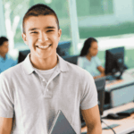 teenage boy smiling in school computer room after successful treatment for psychosomatic symptoms