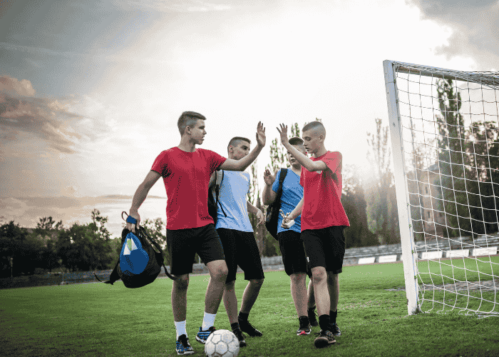 teenage boy with a psychosomatic disorder high-fiving a friend after a soccer game