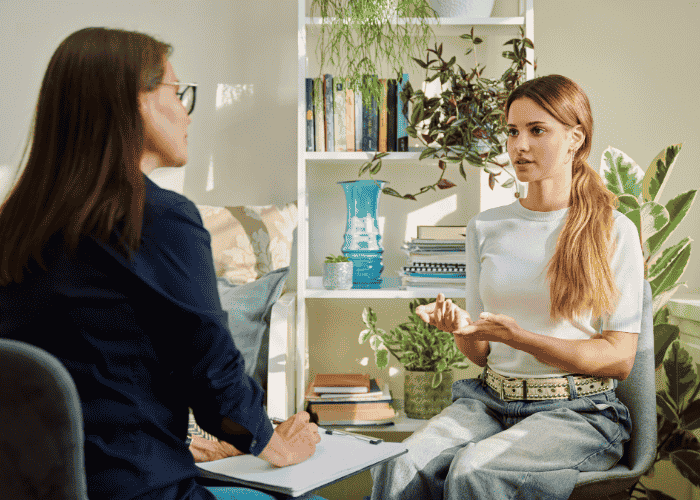 teenage girl sitting with therapist for support with psychosomatic treatment programs for teens
