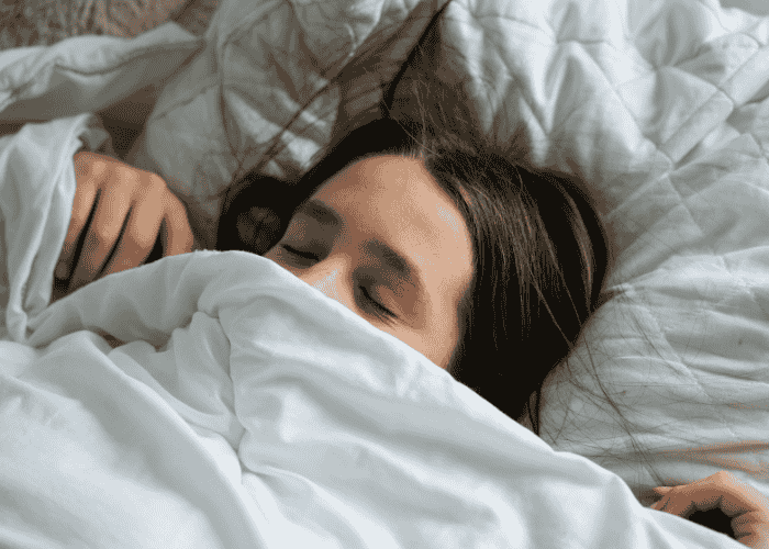 Teenage girl sleeping soundly under her duvet cover because she received treatment for teen nightmares
