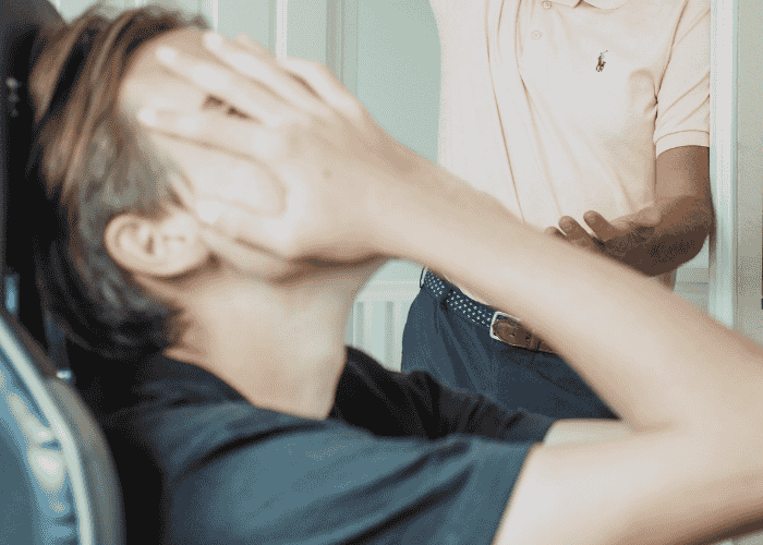 teenage boy with his hands over his face in frustration due to teen irritability