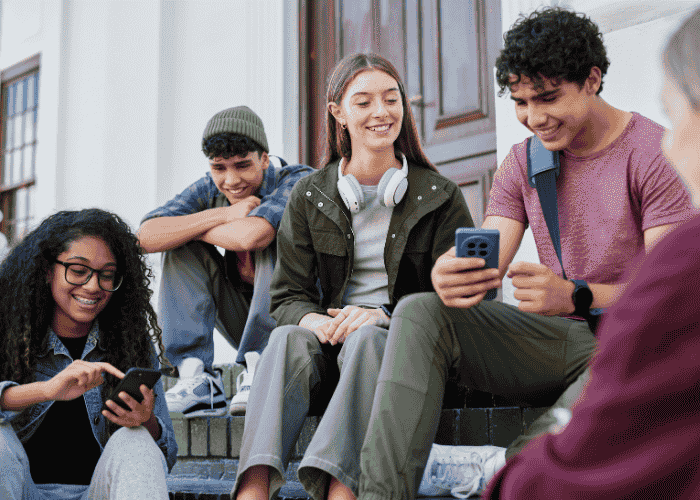 group of teenagers hanging out together laughing and going on their phones after treatment for social & interpersonal symptoms in teens