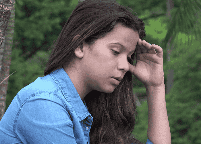 teenage girl sitting outside with head in hands experiencing teen restlessness