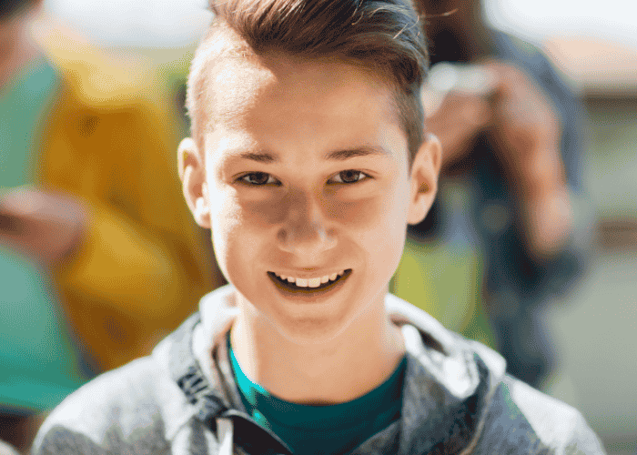 teenage boy outside smiling after receiving treatment for