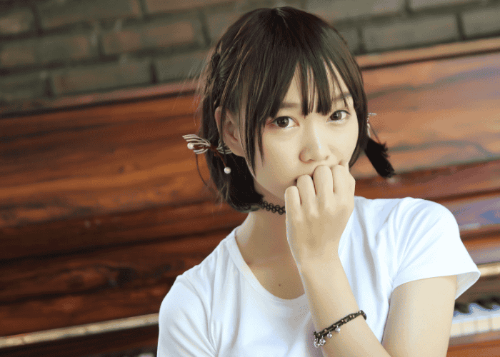 teenage girl standing in front of piano biting nails nervously due to experiencing people-pleasing in teens