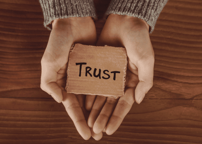 close-up of hands of a teenage girl experiencing teen trust issues cupped holding a piece of card with trust written on it