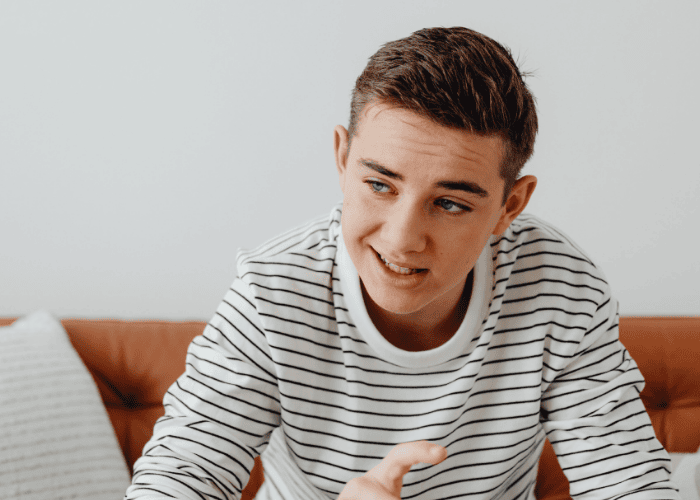 teenage boy experiencing overthinking and negative thought patterns in teens sitting on sofa with worried expression on his face