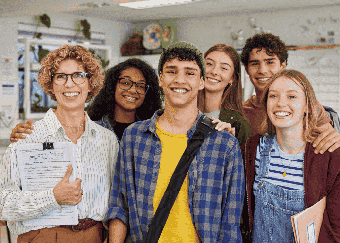 teenage boy smiling after treatment for teen jealousy & insecurity in classroom with group of teen students and teacher
