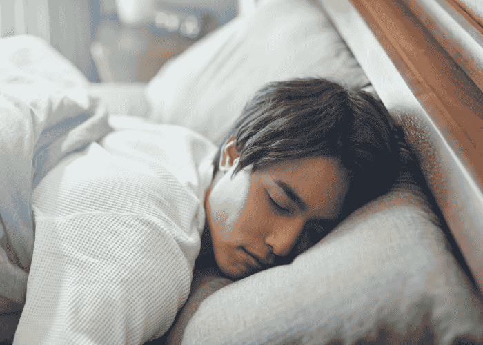 teenage boy sleeping soundly in bed after receiving support for sleep paralysis in teens