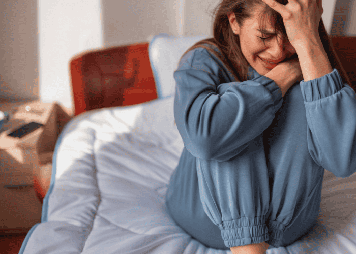 Teenage girl sitting on bed crying experiencing crying spells in teens