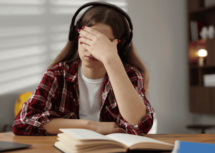 teenage girl studying at home with head in hands experiencing negative thought patterns