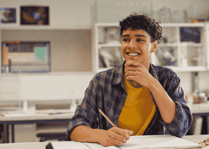 Teenage boy studying smiling after receiving treatment for negative thought patterns