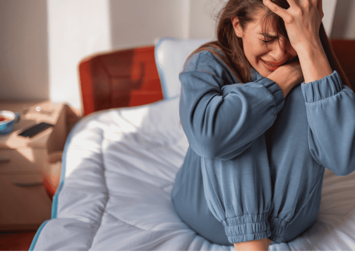 Teenage girl sitting on bed experiencing crying spells