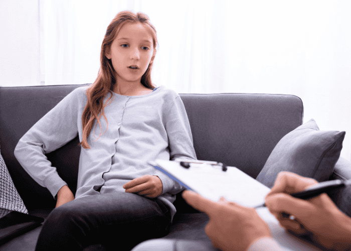 Teenager sitting on sofa in therapy session receiving treatment for mood swings