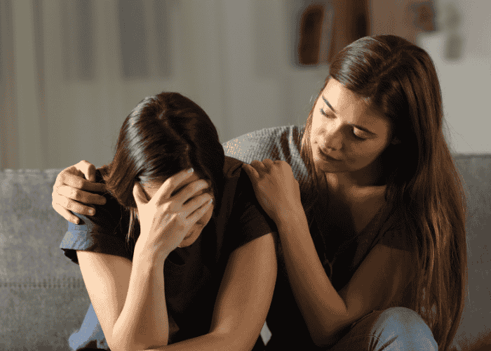 Mother hugging her teenage daughter while the daughter has her head in her hand after experiencing disorientation in teens