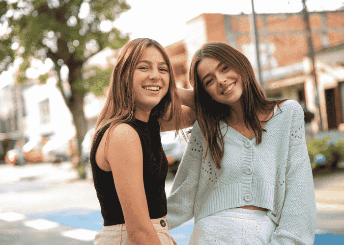 Two teenage girls standing outside smiling at the camera after overcoming disorientation in teens