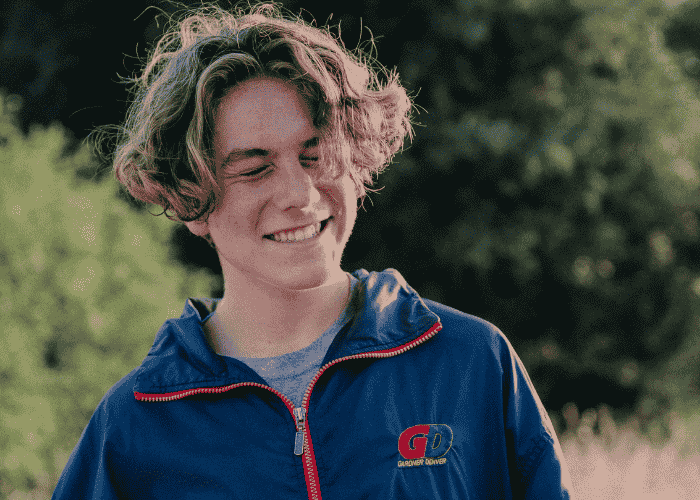 Teenage boy smiling outdoors with his eyes closed after recovering from teen indecisiveness