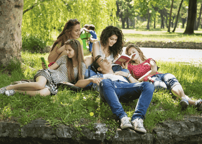 group of teenagers gathered under a tree outside sitting on the ground after having treatment for heart palpitations in teens