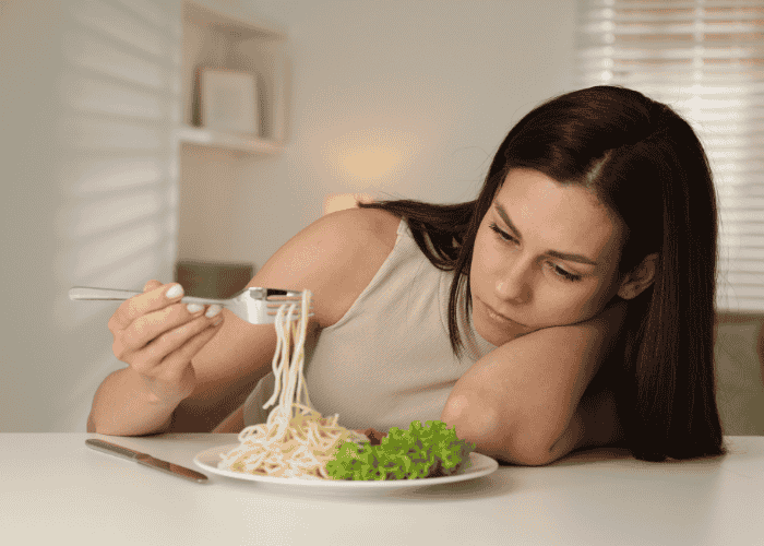 Teenage girl looking at a plate of food struggling with teen loss of appetite