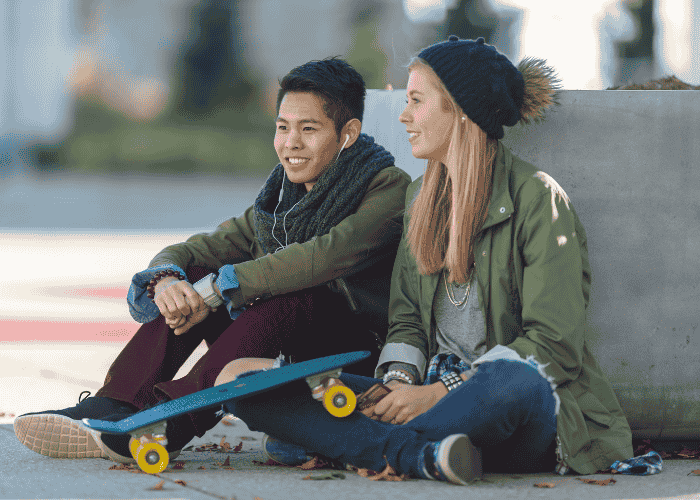 Teenage boy and girl sitting together at the skatepark smiling after having treatment for teen impulsivity