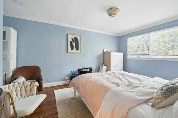 Mission Prep spacious bedroom with light blue walls, white dresser, hardwood floors, and a large window.