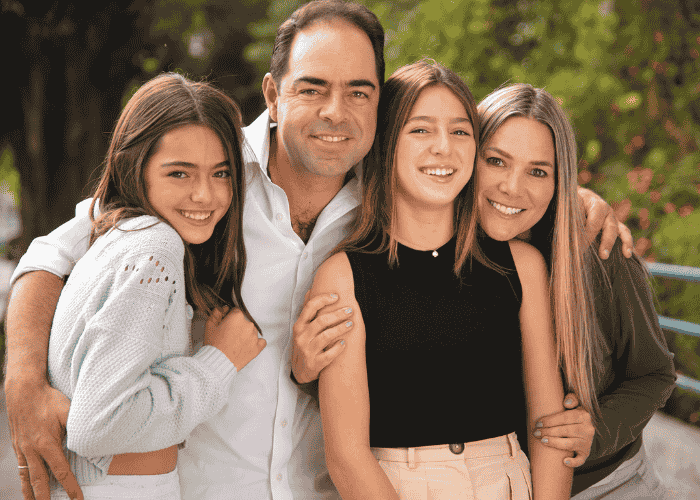Teenage girl with parents and sister outside smiling after support with difficulty talking about feelings
