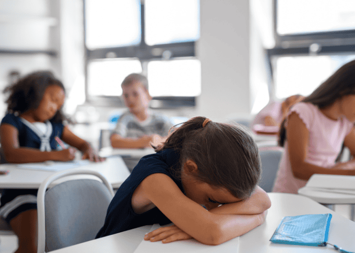 Teenage girl with head on desk in class due to concentration problems