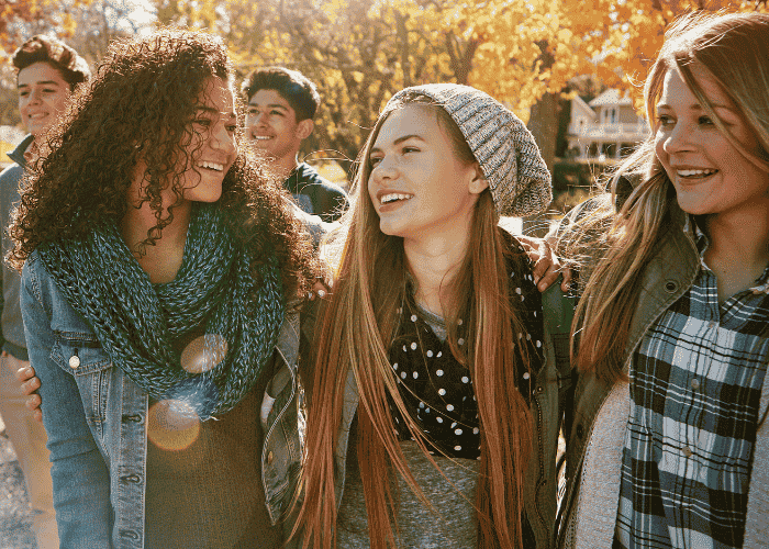 Teenage girl walking in park with friends smiling after support for fear of being judged