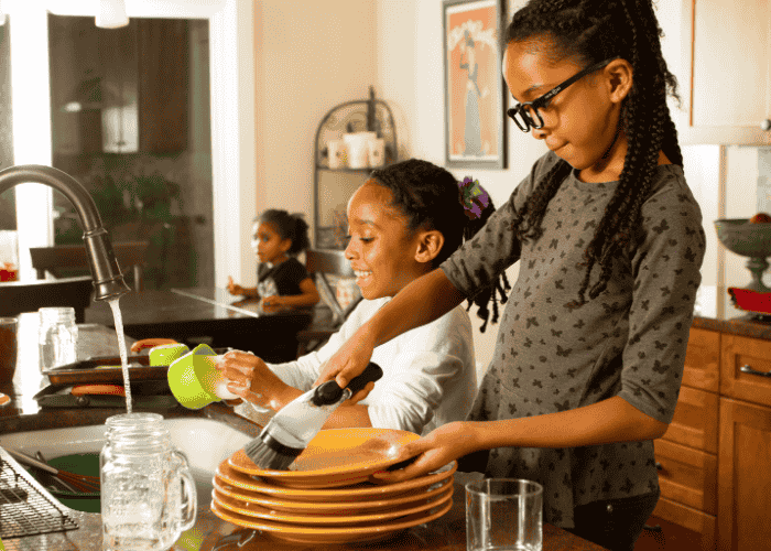 teenage girl doing dishes with her sister in kitchen after support for forgetfulness in teens