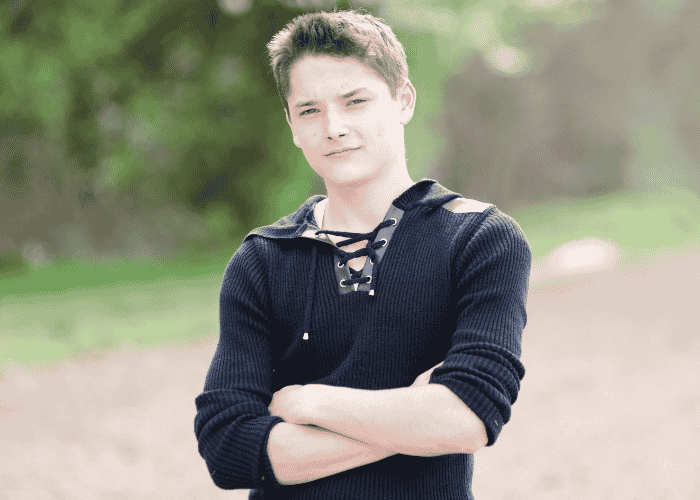 Teenage boy outside at the park looking calm with arms crossed after treatment for hypomania in teens