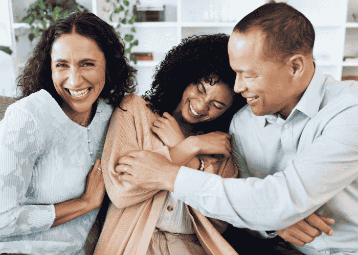 Teenage girl on sofa with mum and dad laughing after support for trust problems in teens