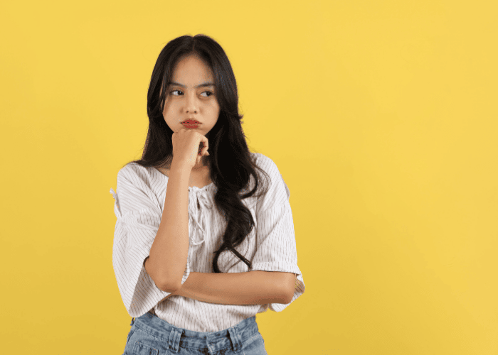 Teenage girl with arm across body and hand on chin looking untrusting due to trust problems in teens