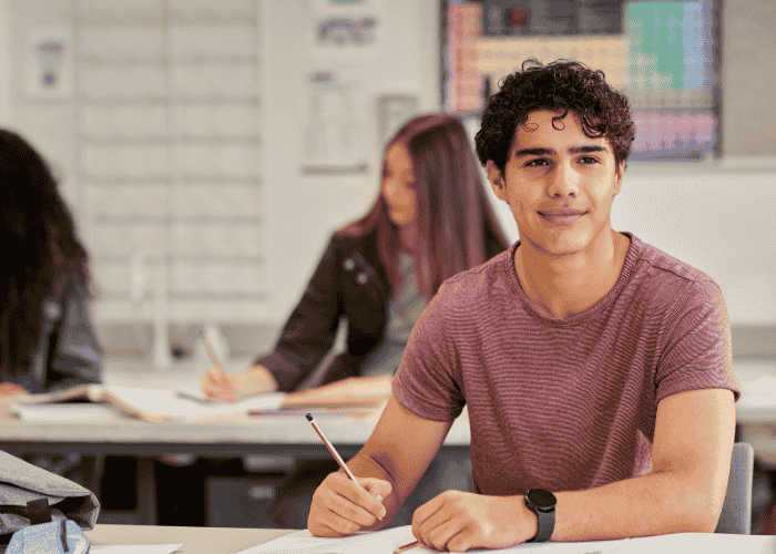 Teenage boy in classroom smiling confidently after treatment for self-criticism in teens
