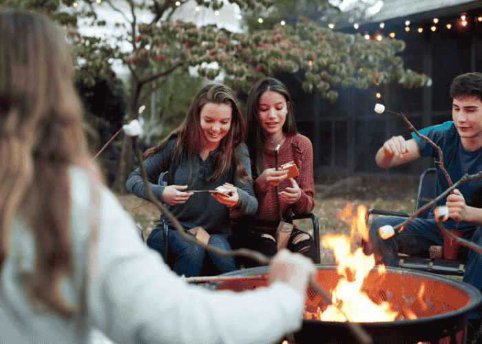 Group of teenage friends having a campfire after receiving treatment for trying too hard to impress others